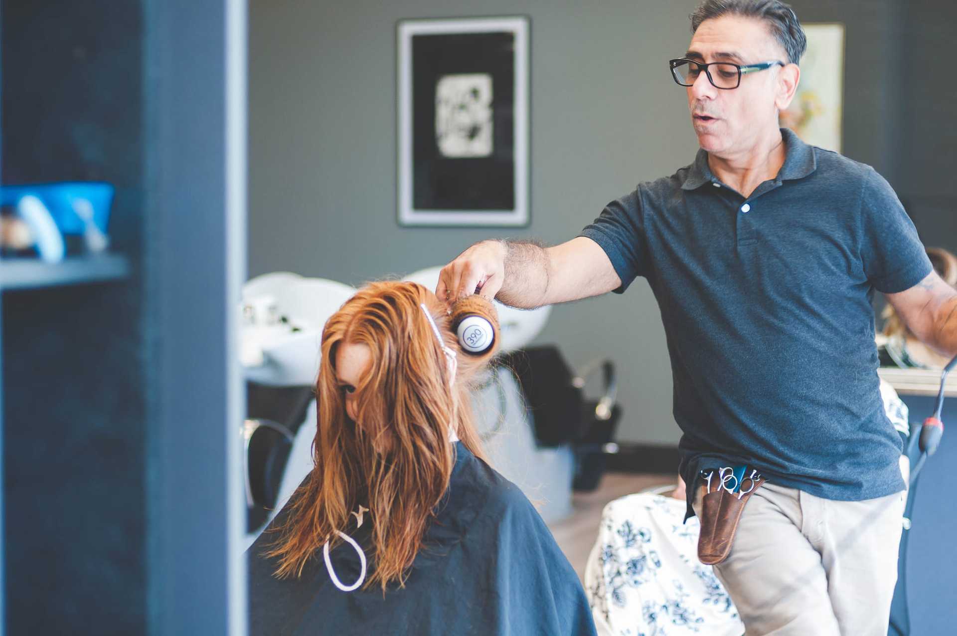 Hairdresser styling a woman's wet hair in a salon.